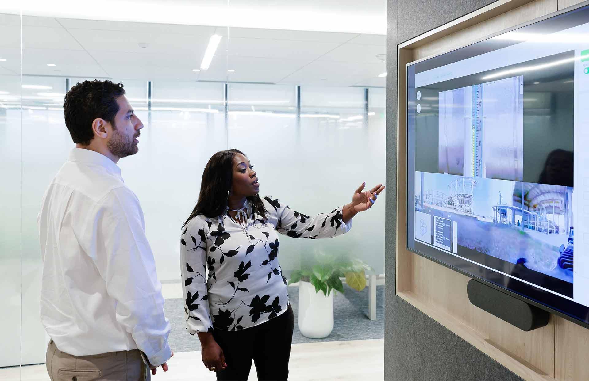 Two 全国快3信誉最好的老平台 employees discussing a large display in a Performance Live digital service delivery center.