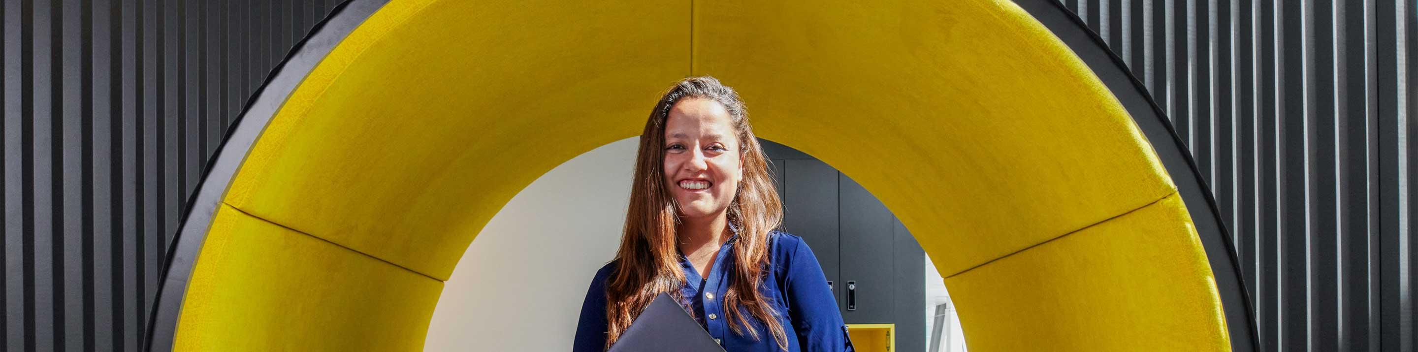 Women holding laptop in front of a big circle yellow structure