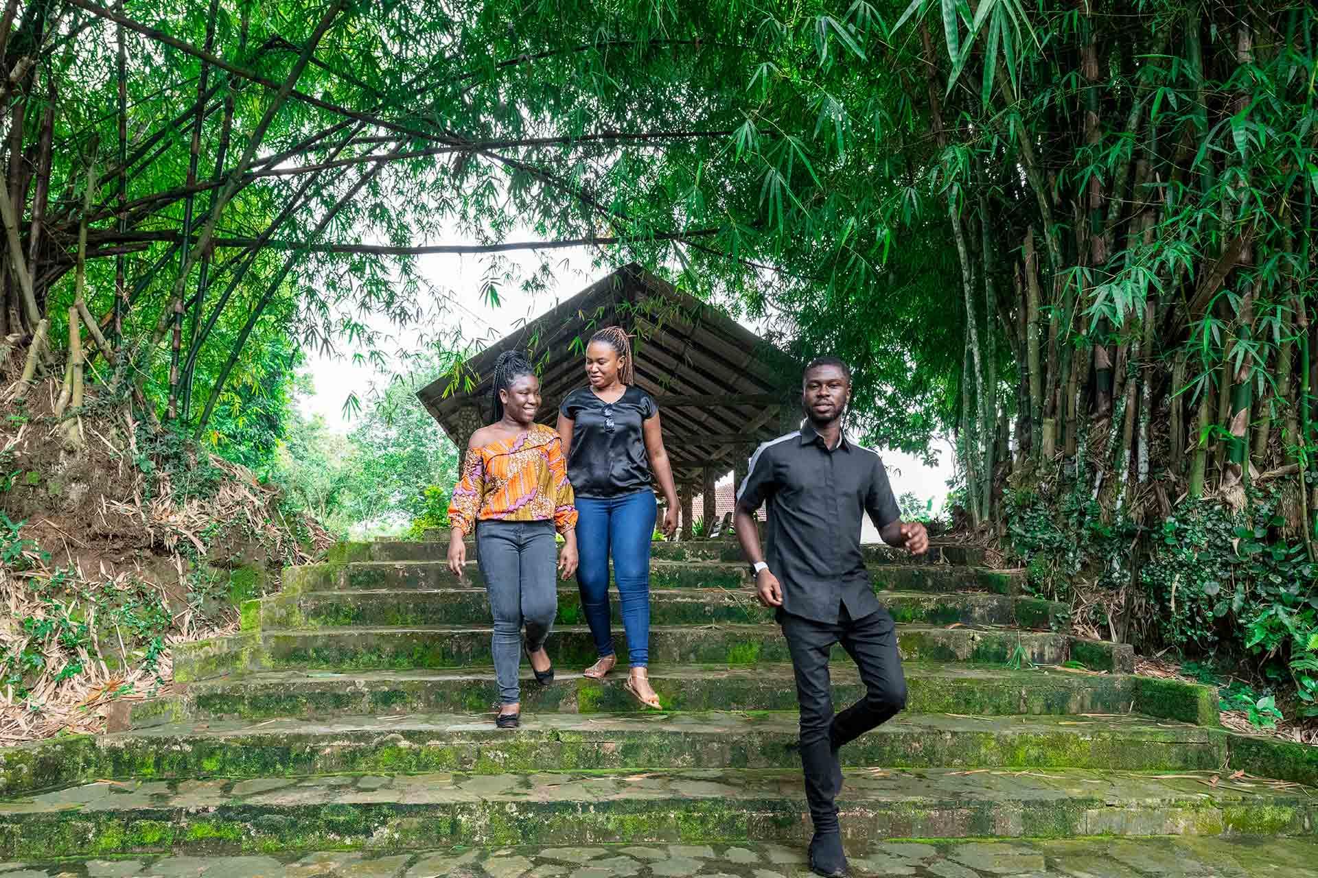 Three people walking down steps through a forest